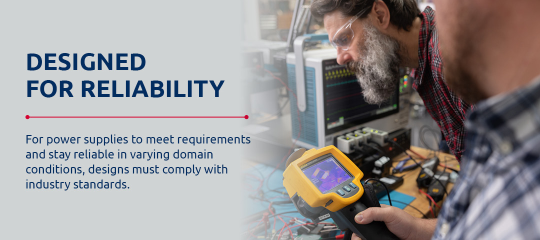 Image of engineers in lab testing design with the text: Designed for reliability | For power supplies to meet requirements and stay reliable in varying domain conditions, designs must comply with industry standards.